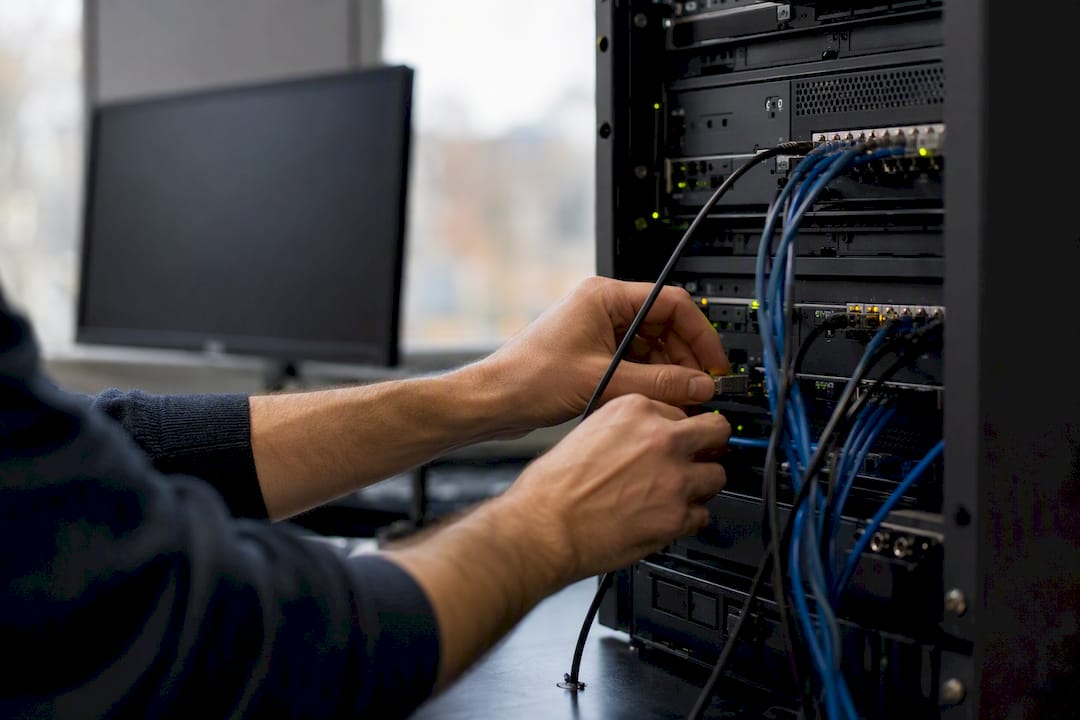 Hands connecting network cables in tech workspace