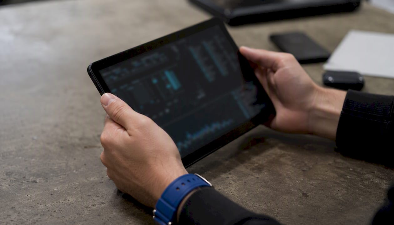 Hands holding tablet showing blurred AI incident data